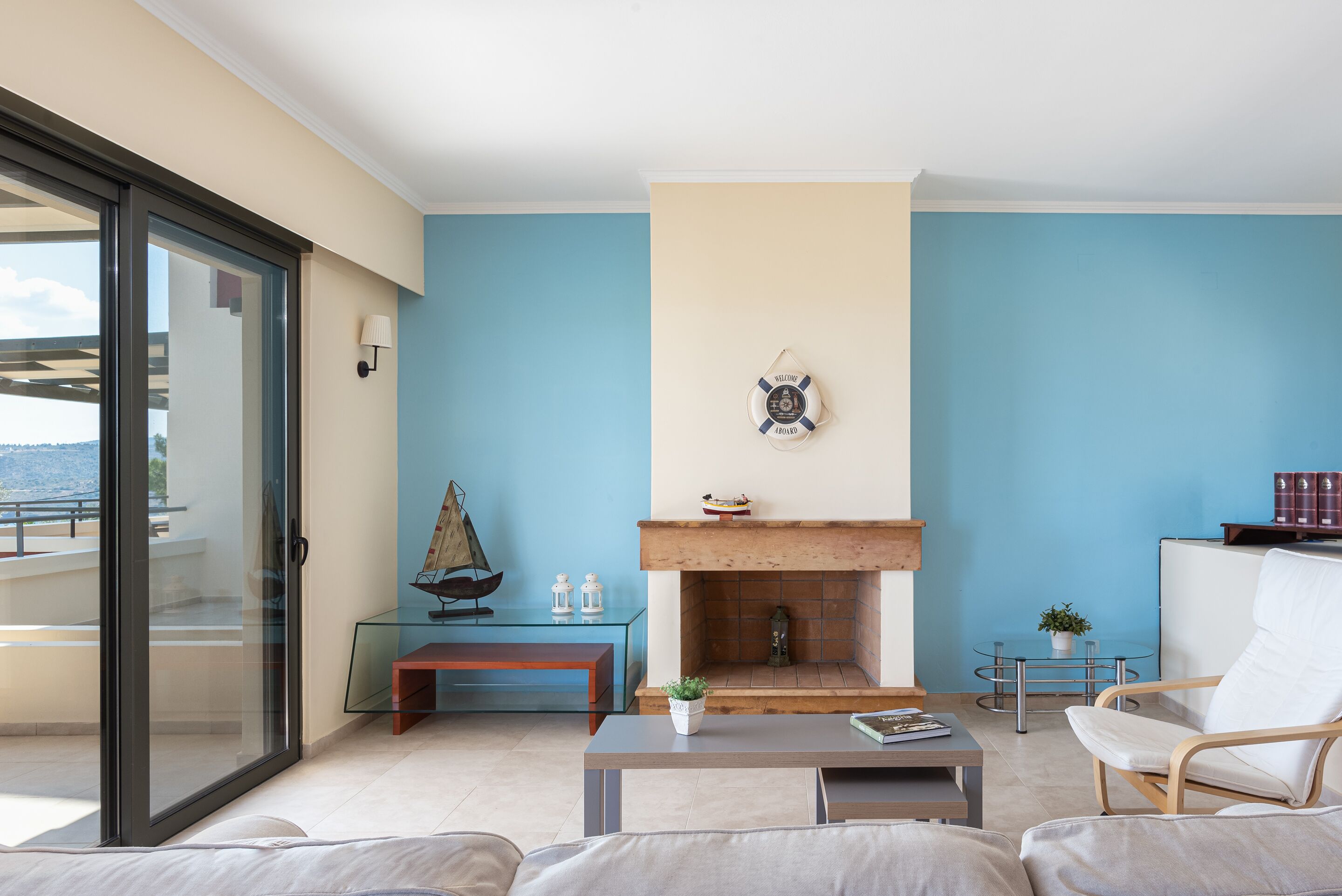 Una sala de estar moderna con una mesa de centro de vidrio, un sofá, una chimenea y vistas al exterior.