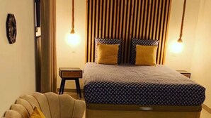 A bedroom with a bed, a sofa, and a small table. - Sandspa 84 (Orange)