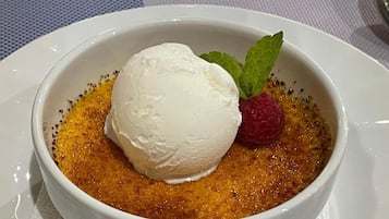A dessert in a white bowl with a scoop of ice cream, a raspberry, and a mint leaf.