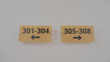 Dos letreros con números y flechas, indicando direcciones o números de habitación.