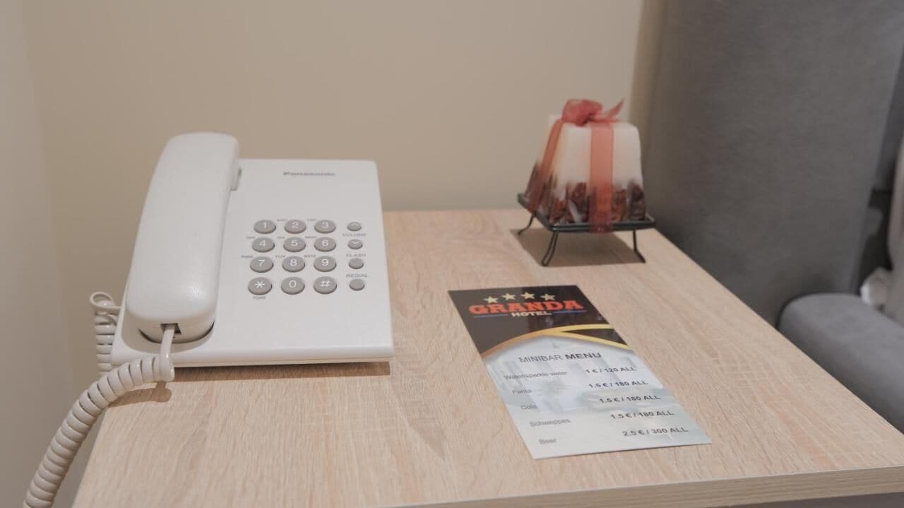 A hotel room with a white telephone, a minibar, and a menu on the table.