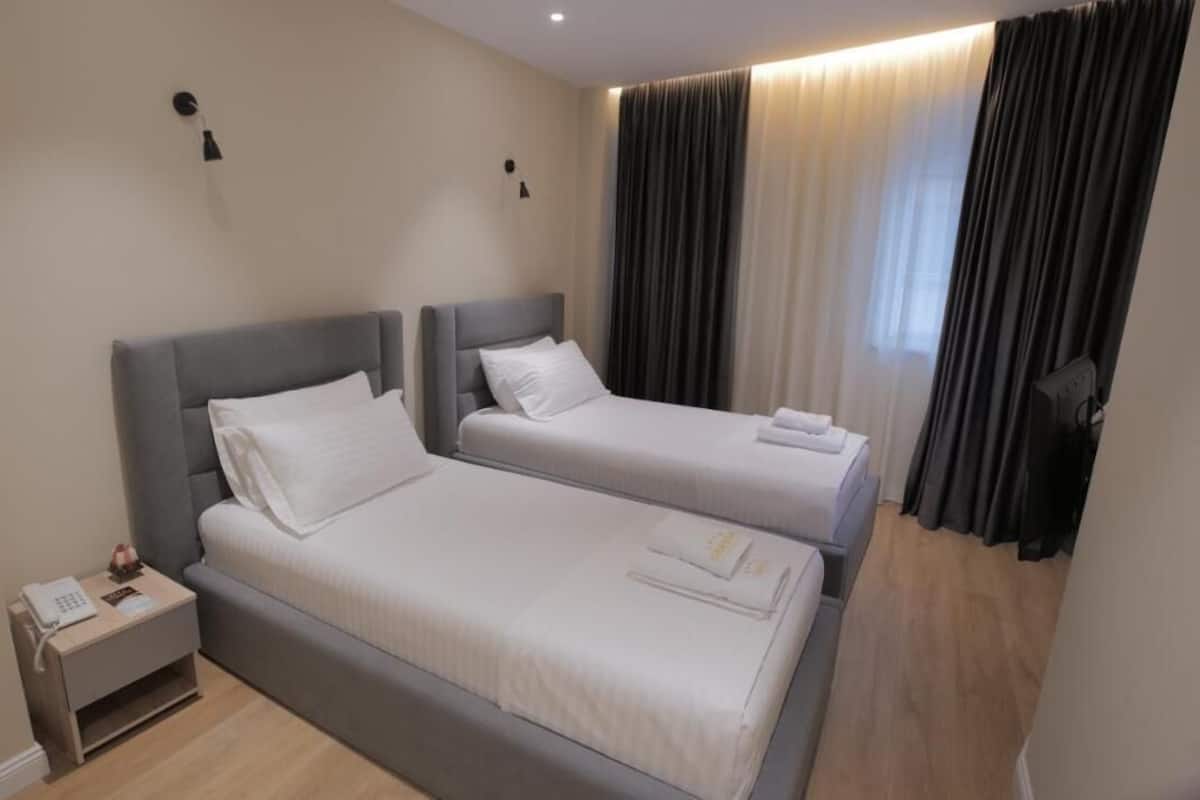 Une chambre d’hôtel avec deux lits simples, une table de chevet avec un téléphone et une télévision.