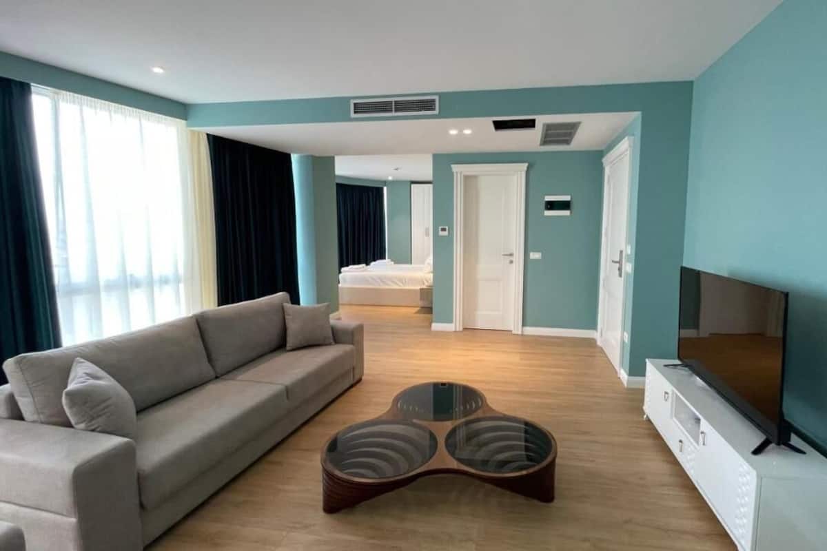 Une chambre d’hôtel moderne avec un canapé, une télévision et une table basse en bois.