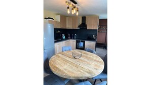 A modern kitchen with wooden cabinets, a built-in oven, and a round dining table with blue chairs.