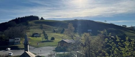 Un paysage rural avec une église, une route et des collines ondulantes.