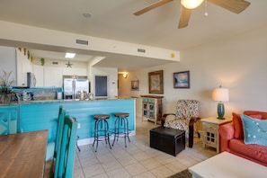 A spacious living area with a kitchen, a dining table, and a red sofa.