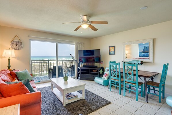 A living room with a sofa, coffee table, TV, and a dining area with chairs.