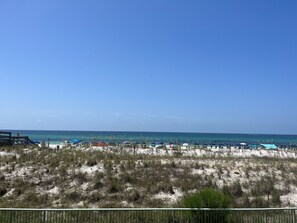 A beach with a clear sky, sandy dunes, and beach umbrellas. - Beachfront with outstanding views! beach set up included! (Okaloosa Island)