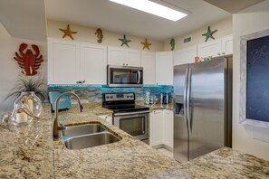 A kitchen with white cabinets, a stainless steel refrigerator, a microwave, and a stove.