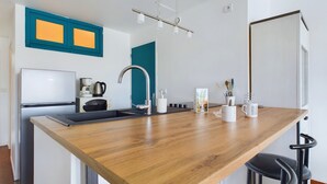 A modern kitchen with a wooden countertop, stainless steel appliances, and a teal accent wall. - 200m from the beach, flat for 4 (Saint-Hilaire-de-Riez)