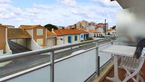 A balcony with a white table and chairs, overlooking a street with buildings and a clear sky. - 200m from the beach, flat for 4 (Saint-Hilaire-de-Riez)