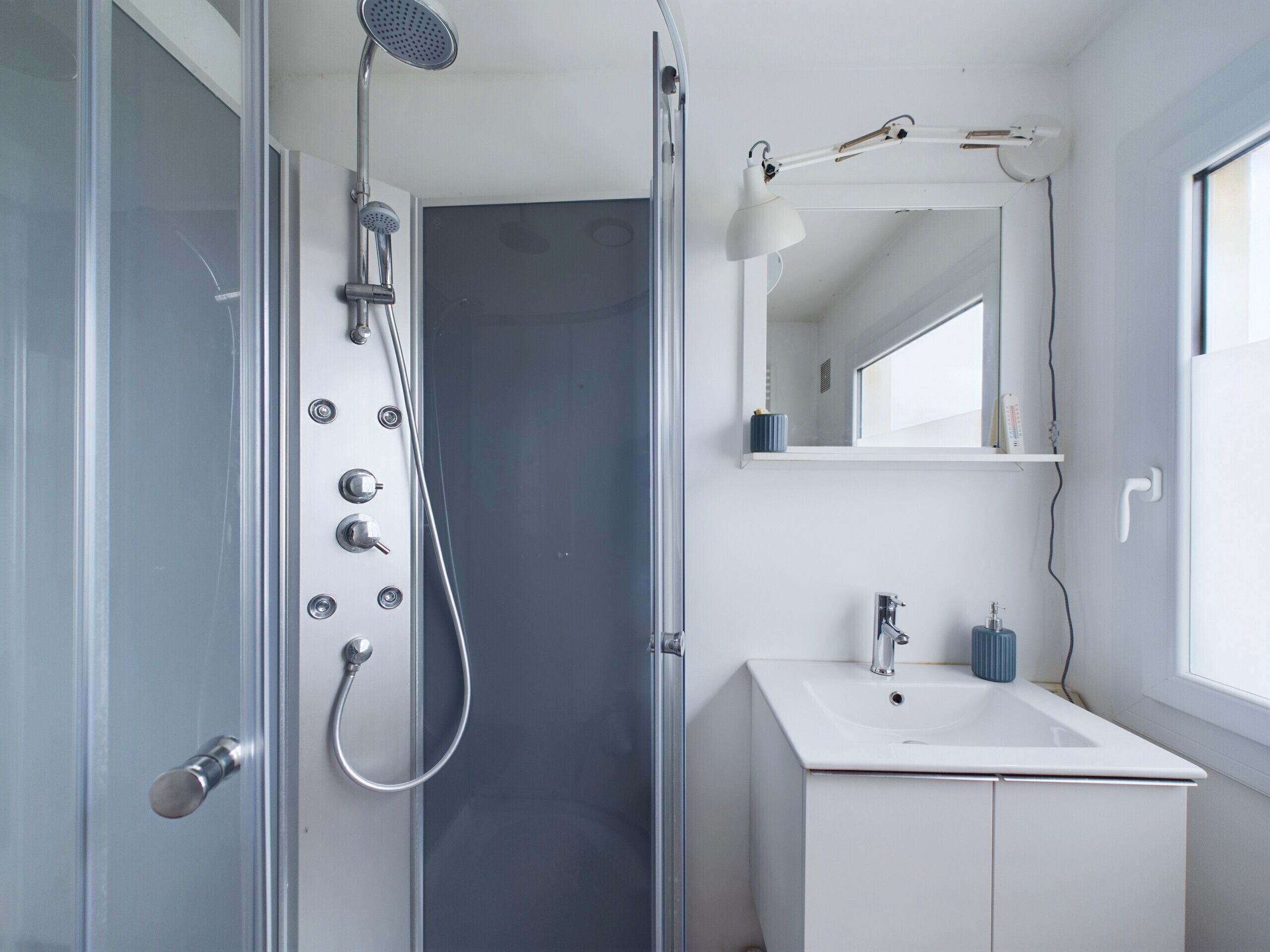A modern bathroom with a glass shower enclosure, a white sink, and a mirror above the sink.