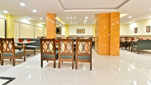 A hotel lobby with a central seating area, a reception desk, and a dining area. - Hotel Comfort Court (Dalhousie)