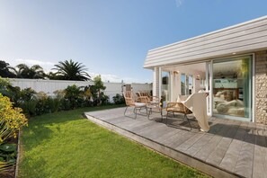 A modern house with a patio, outdoor seating, and a view of the backyard. - The Endless Summer Home - Where Waves and Town Unite (Mount Maunganui)