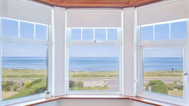 Une chambre d’angle dotée de trois grandes fenêtres offrant une vue sur le paysage côtier.
