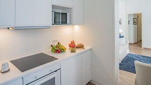 Una cocina moderna con armarios blancos, microondas integrado y una encimera con productos frescos.