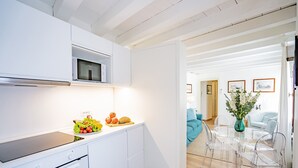 Eine moderne Küche mit weißen Schränken, einer Mikrowelle und einem Essbereich mit klaren Stühlen und einem Glastisch.
