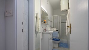 Un baño con inodoro, lavamanos y zona de ducha.