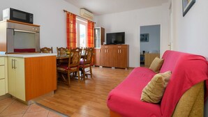 Un espacio habitable compacto con kitchenette, comedor y un sofá rojo.