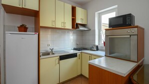Una cocina con refrigerador, estufa, microondas y ventana.