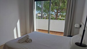 A hotel room with a large bed, a bedside table, a lamp, and a view of trees through the window. - Casa Marisa, Villa CON Piscina Delante DEL MAR (Les cases de Alcanar)