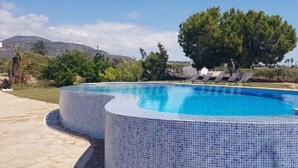 A round swimming pool with a tiled edge, surrounded by lounge chairs and trees. - Casa Marisa, Villa CON Piscina Delante DEL MAR (Les cases de Alcanar)