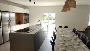 A modern kitchen with a central island, stainless steel appliances, and a dining area with a patterned tablecloth. - Casa Marisa, Villa CON Piscina Delante DEL MAR (Les cases de Alcanar)