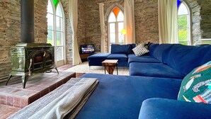 Un salon chaleureux avec un mur en pierre, une cheminée, un canapé bleu et un téléviseur.