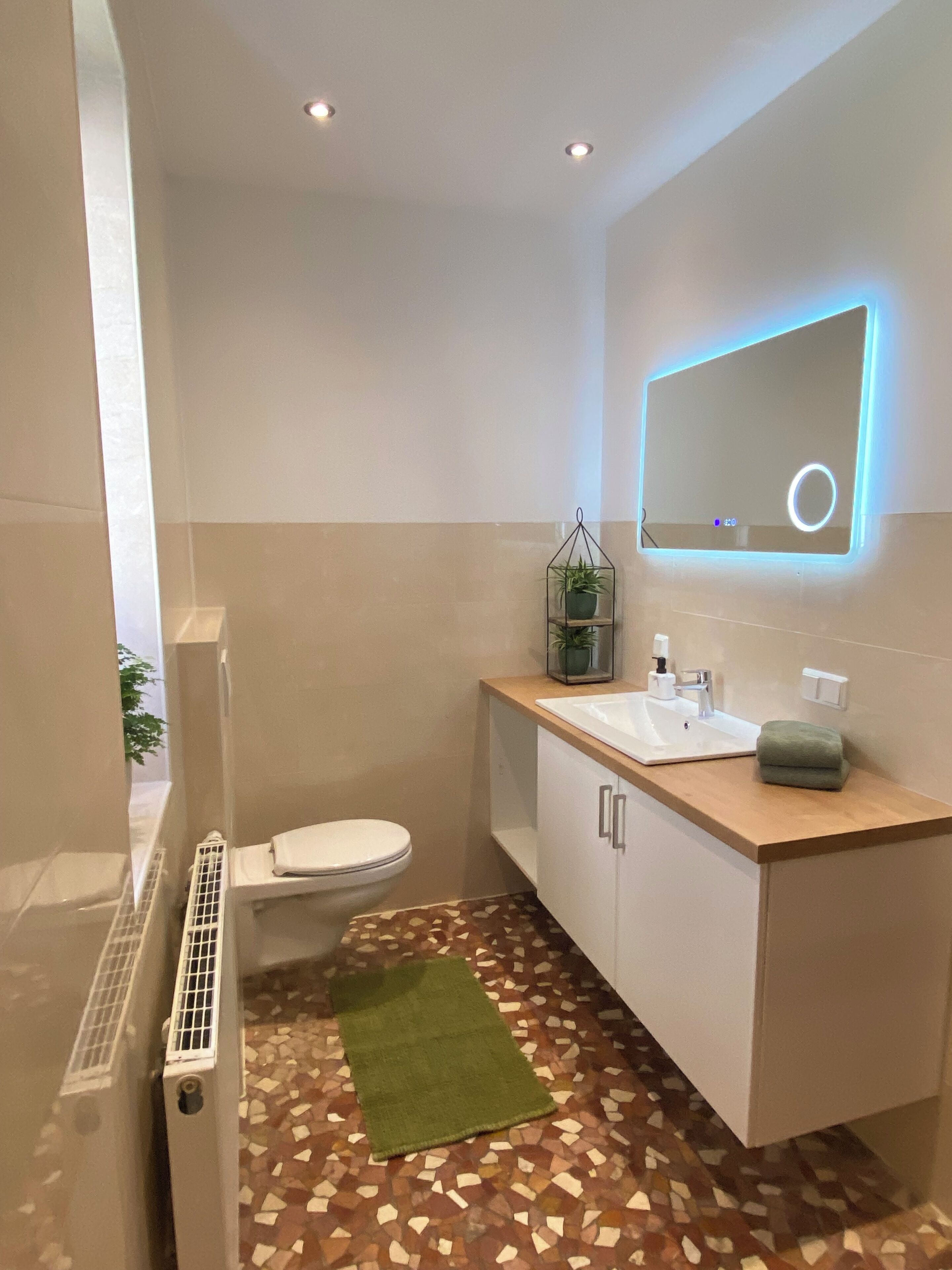 Ein modernes Badezimmer mit Toilette, Waschbecken und Spiegel.