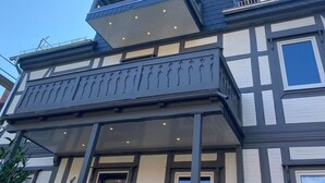 Um edifício de vários andares com uma varanda saliente no segundo pavimento e um design de telhado angular peculiar.