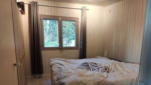 A wooden room with a bed, a window with curtains, and a door. - Near-sea rental (Quend)