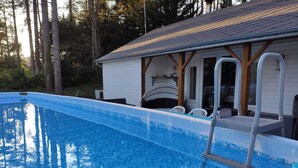 A swimming pool with a ladder, surrounded by a wooden deck and white chairs. - Near-sea rental (Quend)