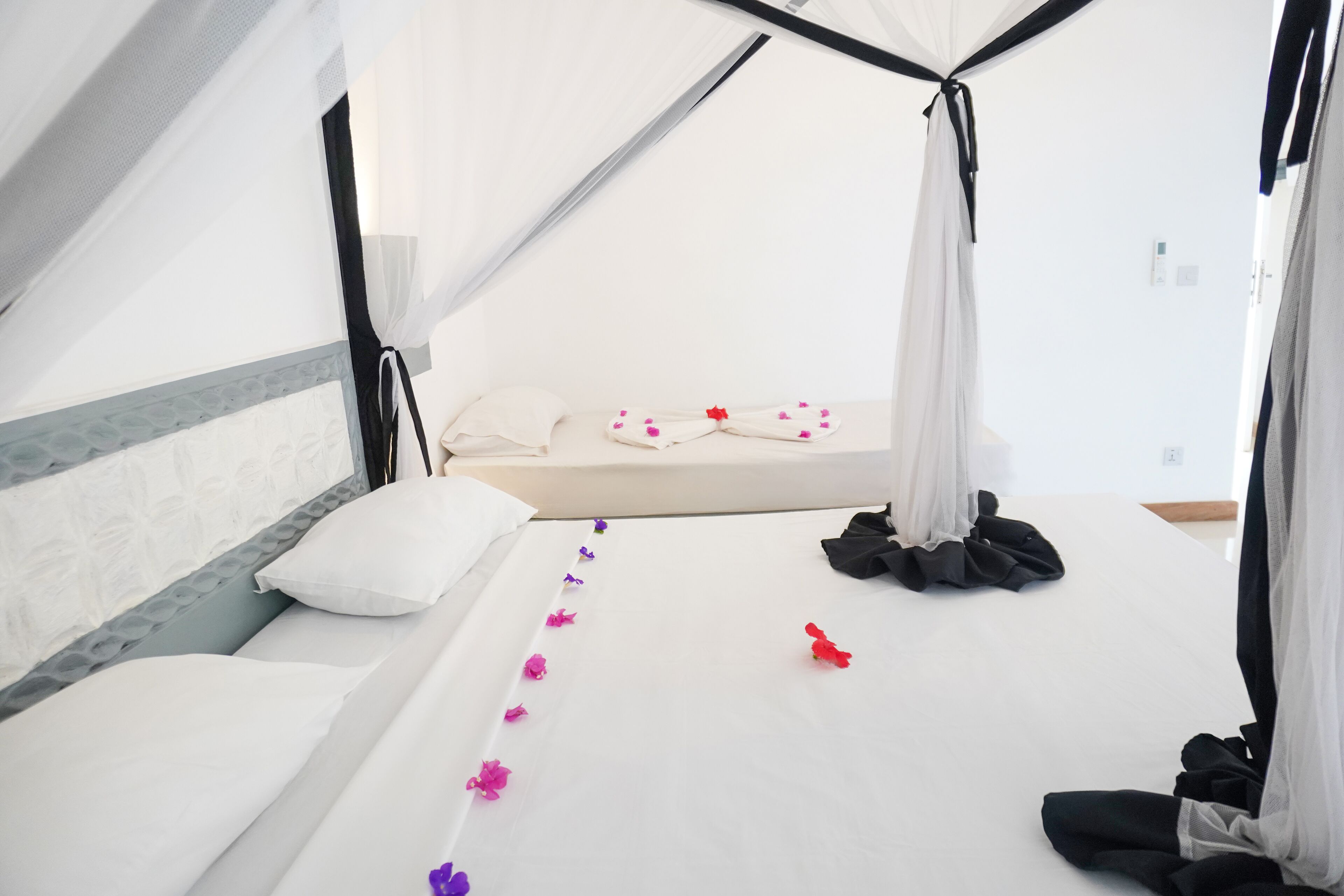 Un lit bien fait, avec des draps blancs, un baldaquin et une guirlande de fleurs décorative.