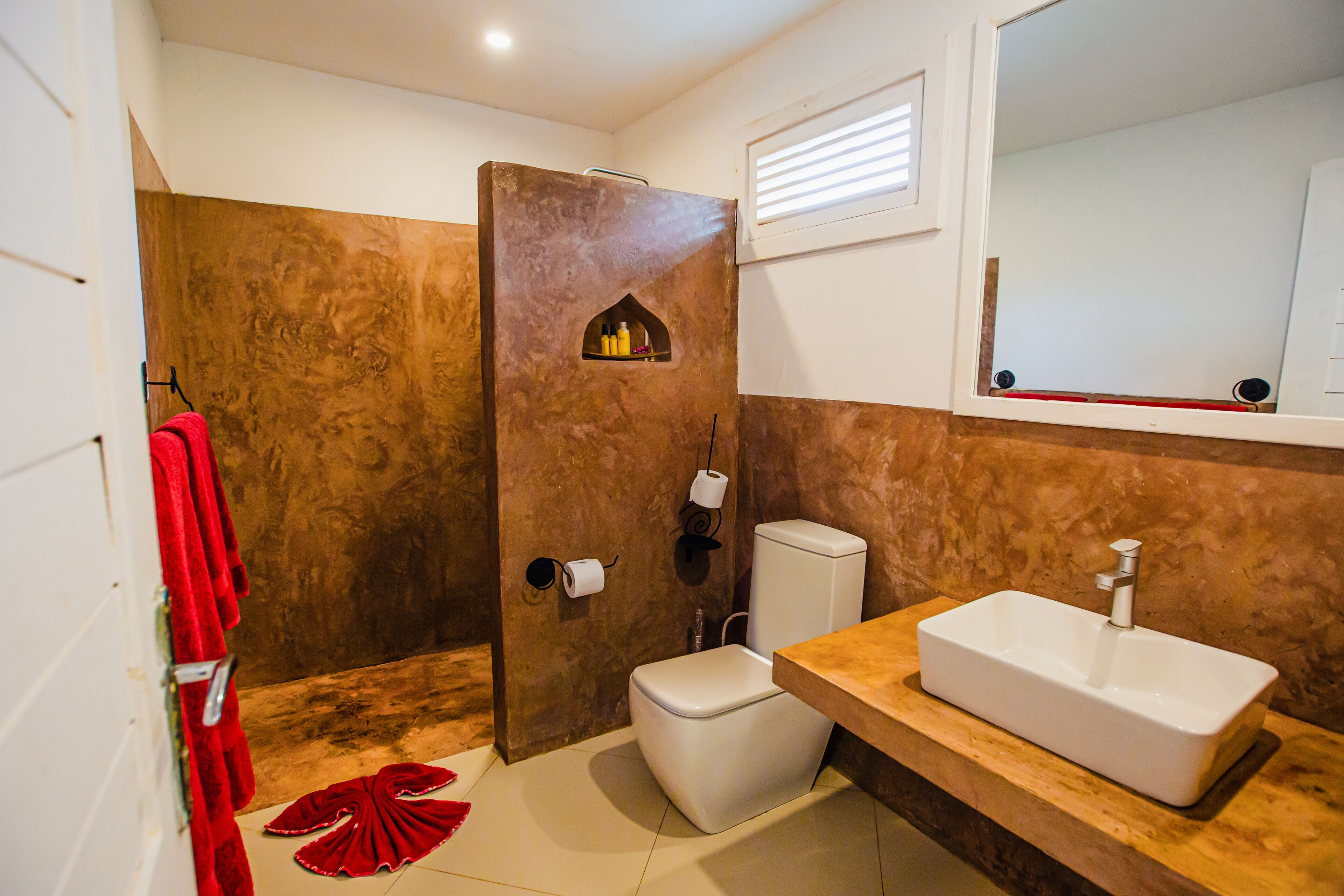 A bathroom with a shower, toilet, sink, and a mirror.
