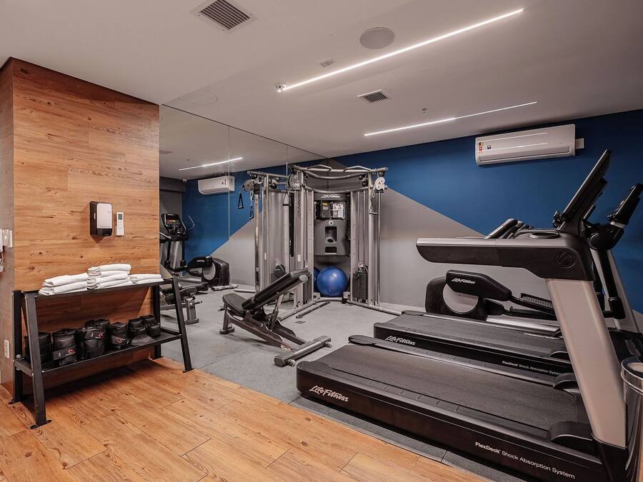 A gym with cardio equipment, weight machines, and a mirrored wall.