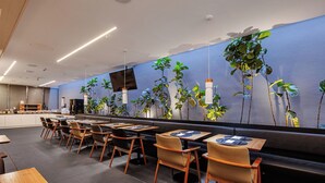 A modern restaurant with a long counter, multiple tables, and chairs.