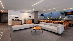 Un interior moderno con un sofá modular, una mesa de centro redonda, comedor con sillas de madera y una cocina al fondo.