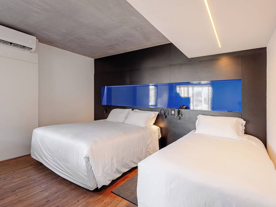 Habitación de hotel con dos camas, diseño moderno, un espejo grande y aire acondicionado en el techo.