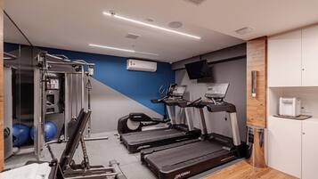 Un gimnasio con cintas de correr, máquinas de pesas y pelotas de ejercicio.