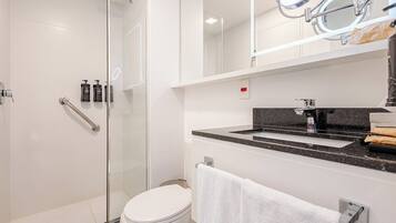 A modern bathroom with a glass shower enclosure, a white toilet, a vanity with a black countertop, and a towel rack.
