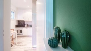 Een moderne keuken met witte kastjes, een marmeren aanrecht en een groene accentmuur.