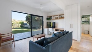 A modern interior with a sofa, a dining table, a TV, and a kitchen area.