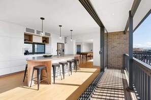 Contemporary kitchen with central island, bar stools, and large window offering a view of the outdoors.