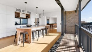 A modern kitchen with a bar area, a pool table, and a balcony with a view.
