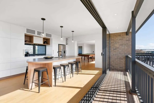 Une cuisine moderne avec un coin bar, une table de billard et un balcon offrant une vue agréable.