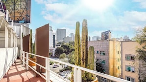 A balcony with potted cacti, a cityscape with buildings, and a clear sky. - Upscale Polanco | Steps to Metro, Dining & Parks (Ciudad de México)