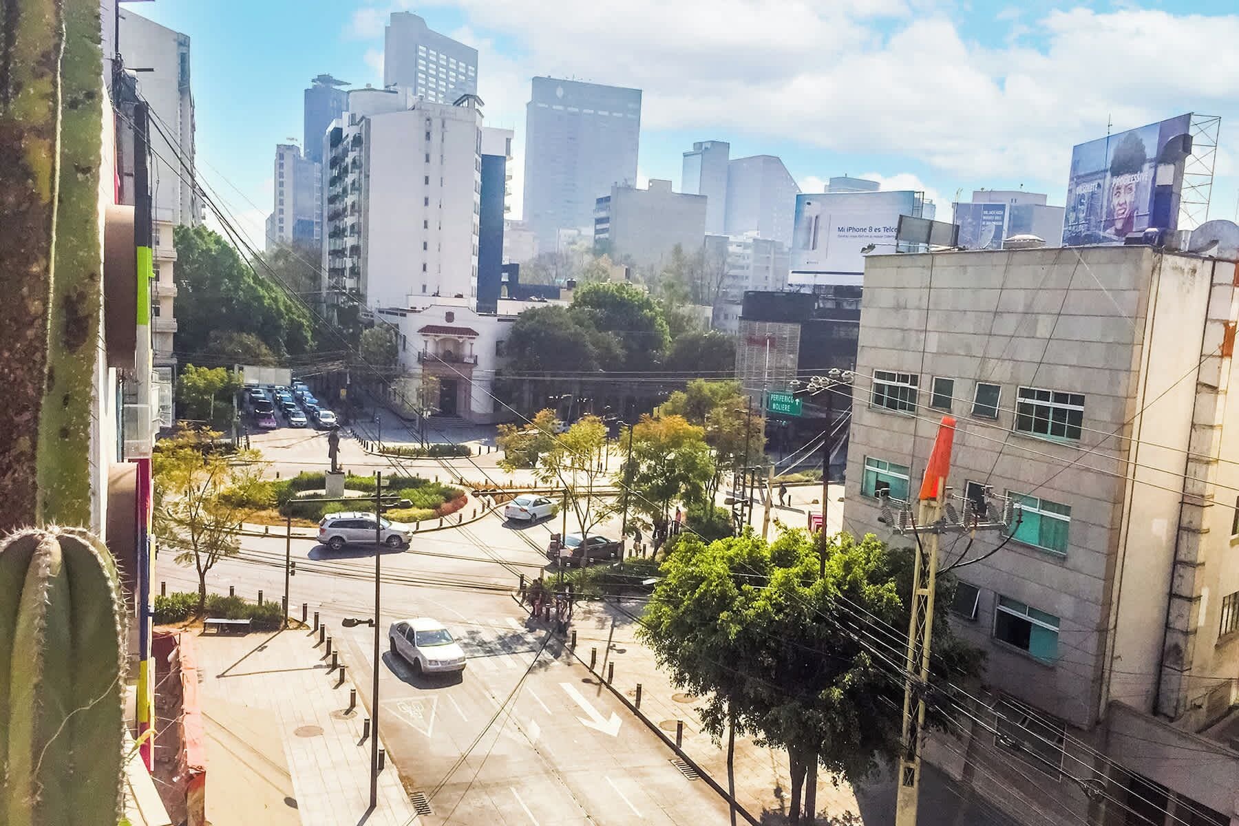 A cityscape with buildings, a statue, and a road with cars.