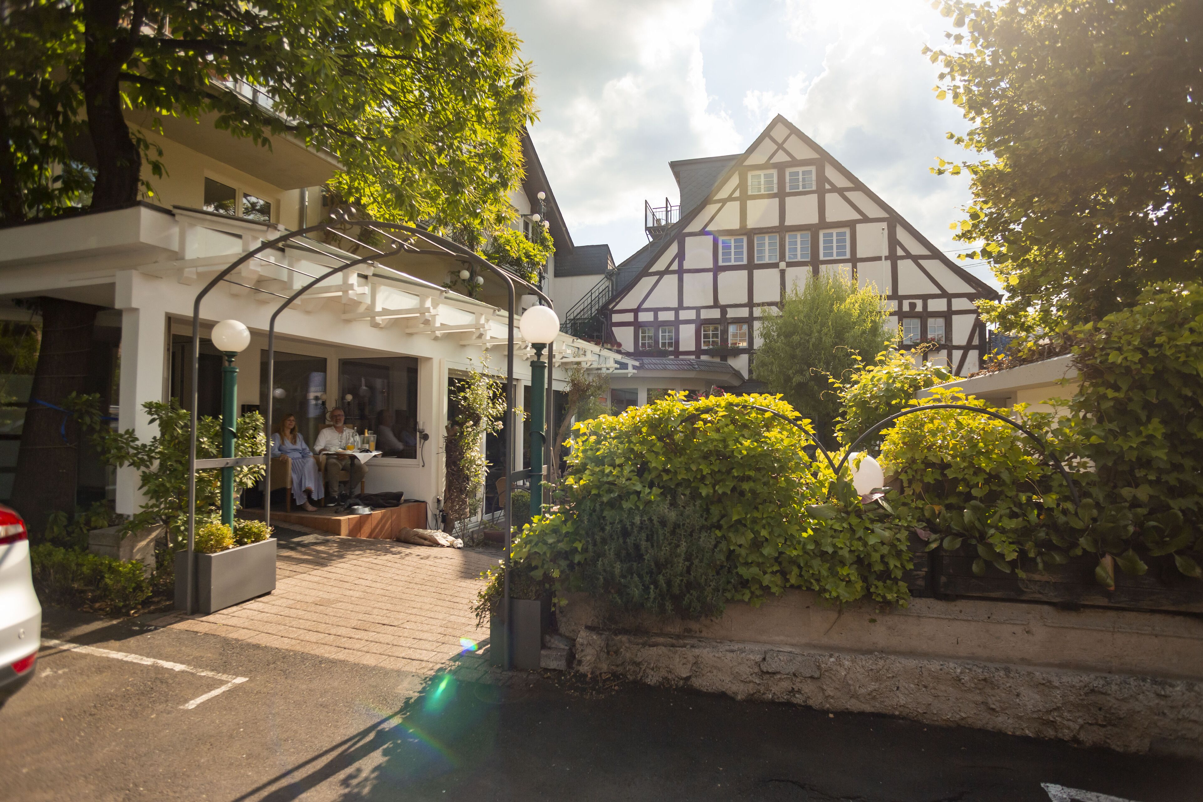 A traditional European-style building with a balcony, a wooden deck, and a small garden area with potted plants.