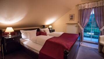 A bedroom with a large bed, two bedside tables with lamps, a window with curtains, and a view of the outdoors.