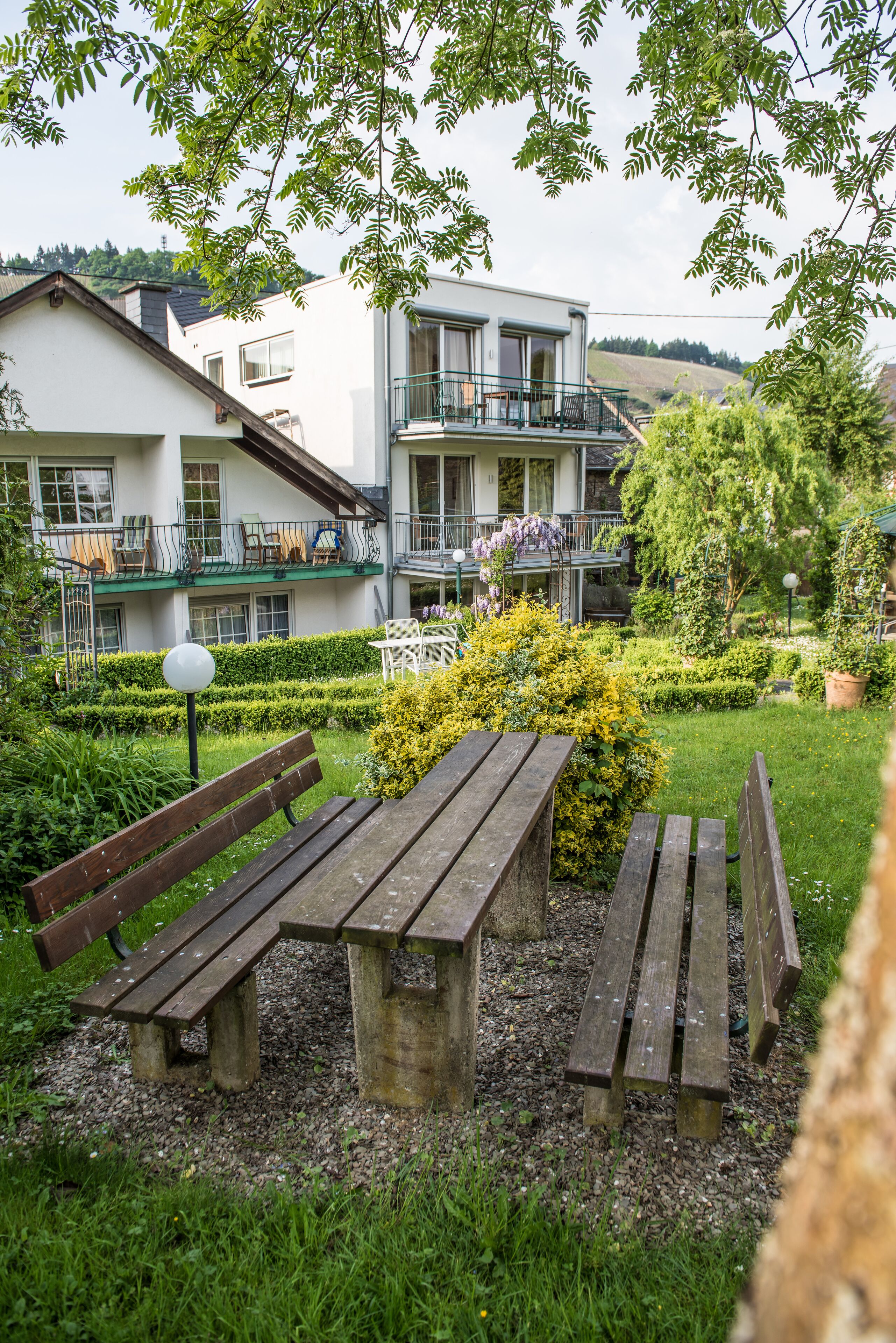 Een binnenplaats met een houten bankje, een tafel en een verzorgde tuin.